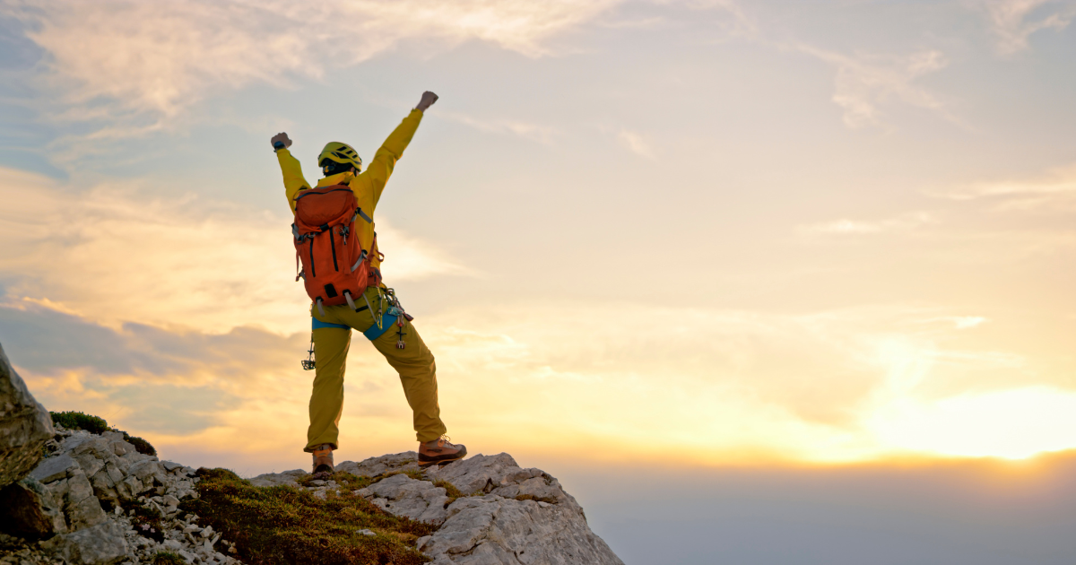 Man on mountain who has reached his goal and is pursuing his dreams